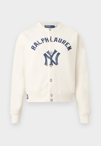 Άσπρο μπουφάν με κουμπιά τύπου snap, με μπλε φθαρμένο κείμενο "RALPH LAUREN" και διασταυρούμενο λογότυπο NY στο στήθος, με ριμπ μανσέτες και τελείωμα.