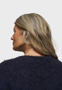 Navyblauwe mohair trui met een gestructureerd oppervlak, ronde halslijn en een relaxte pasvorm, zijaanzicht getoond met los, golvend haar.