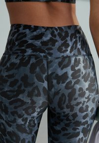 Korkeavyötäröiset leggingsit tummansinisellä mustalla leopardikuviolla. Ominaisuuksina sileä pinta ja erottuvaommeltus.