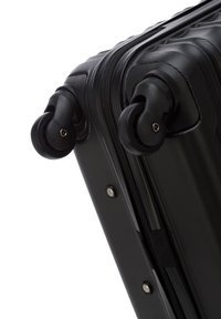 Hard-shell black suitcase with textured surface, dual 360-degree spinner wheels, and a robust zipper for secure closure.