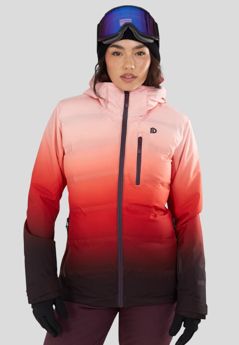 Roze-naar-rode gradient pufferjack met een ritsborstzak, verstelbare capuchon en donkere manchetten. Gecombineerd met een zwarte beanie en een paar goggles.