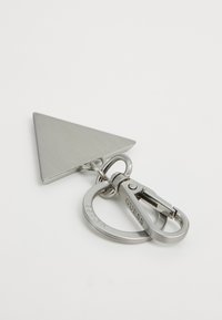 Silver triangular keychain with round ring and clasp, both engraved with the brand name "GUESS," on white background.