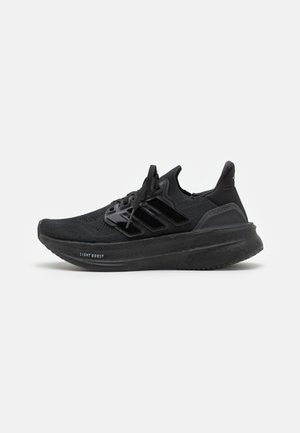 Czarny but do biegania Adidas Ultraboost z dzianą cholewką, trzema paskami, sznurowadłami i grubą wyściełaną podeszwą oznaczoną "Light Boost."