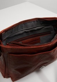 Bruine leren tas met een met rits afgesloten hoofdvak, met een gevoerde binnenkant met een geruit patroon en een kleine binnenzak met rits.