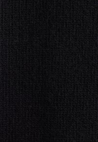 Gros plan sur un tissu noir tricoté avec des boucles de fil texturées visibles et un motif côtelé.