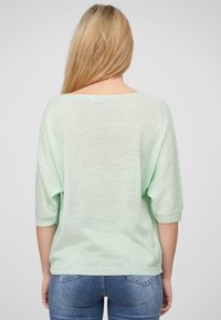 Pull en mint vert surdimensionné avec une coupe ample, des manches 3/4 et un motif en tricot texturé. La vue de dos montre un col arrondi et un tissu doux.