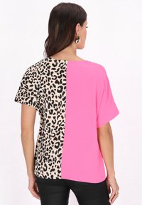 T-shirt a maniche corte con un pannello in stampa leopardata beige e marrone su un lato e un lato in rosa brillante; tessuto morbido e strutturato.