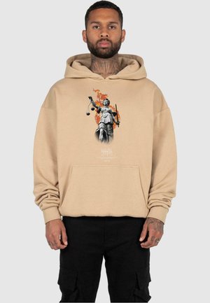 Beige hettegenser med frontlomme, med et grafisk motiv av en statue som holder vekter og et sverd, med flammer i bakgrunnen.