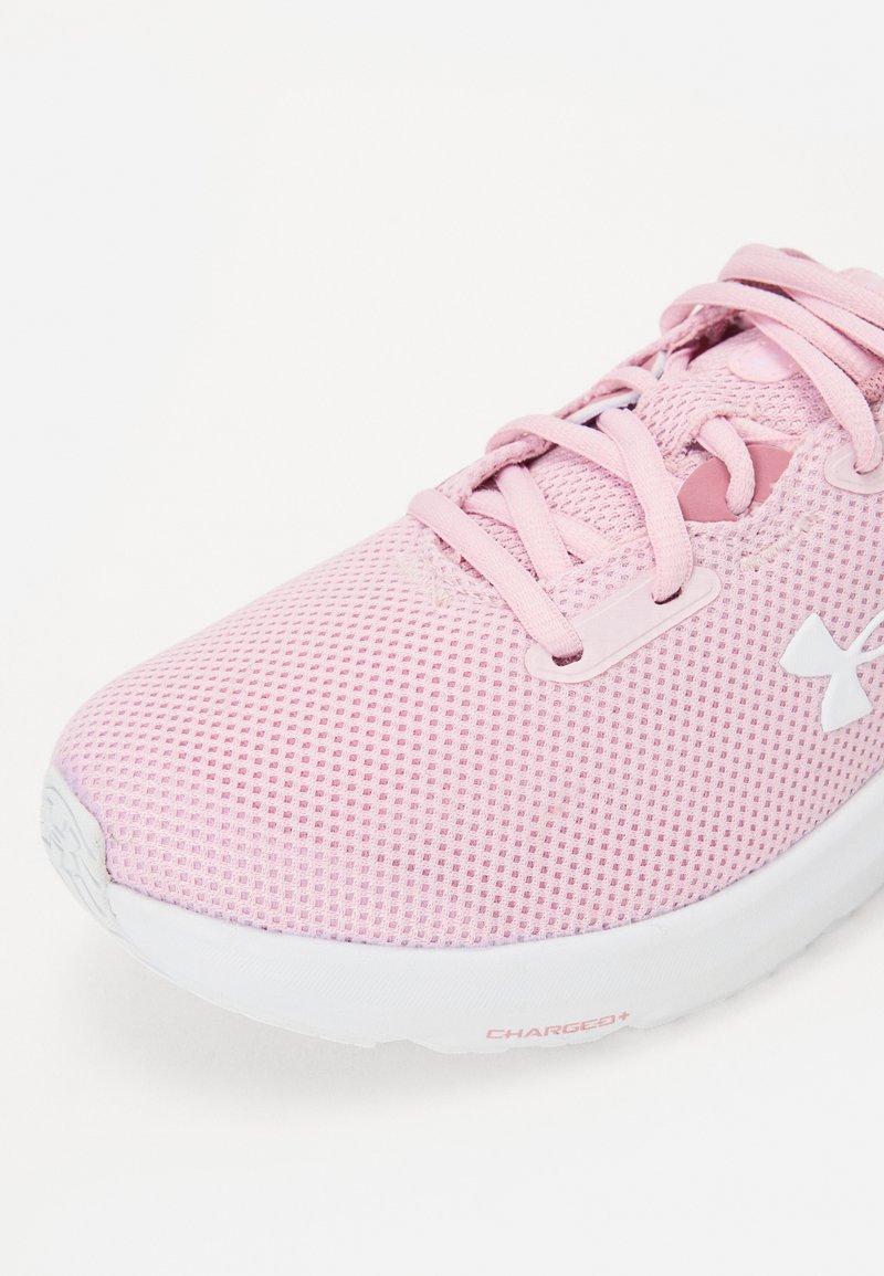 Chaussure de sport rose clair avec une tige en mesh respirant, des lacets et une semelle blanche arborant le marquage "CHARGED+". Bout rond et motif texturé.