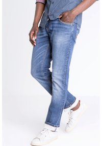 Ljusblå denimjeans med rak passform, som har en blekt tvätt, fem fickor och ljusa sömdekor. Bärs tillsammans med vita sneakers.