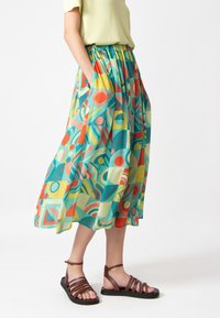 Multikleurige, gemusterde midi-rok met levendige geometrische vormen in teal, rood, geel en crème; elastische tailleband; zijzakken.