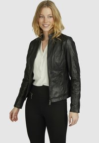 Black leather jacket with a fitted design, zippered front, and side pockets. Paired with a white button-up shirt and black pants.
