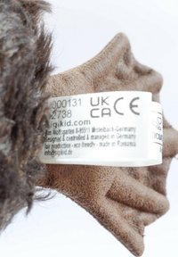 Soft plush toy featuring brown fur, a textured paw, and a label with product details and care instructions. Eco-friendly materials are noted.