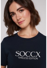 T-shirt en coton bleu marine avec le texte blanc "SOCCX TIMELESS EDITION". Col rond et manches courtes, texture lisse, design décontracté.