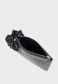 Czarna skórzana kopertówka z uchwytem w stylu scrunchie, zamkiem błyskawicznym i srebrnymi okuciami z logo. Wnętrze wyłożone jest czarną tkaniną.
