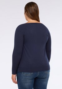 Pulover bleumarin cu mâneci lungi ribbate și tiv, având un design cu spate decupat. Purtați-l cu blugi din denim. Textură netedă.