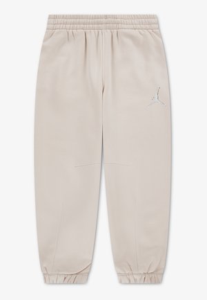Beige jogger pants with elastic waistband and cuffs, featuring a small silver Jumpman logo on the upper left leg. No other visible details.