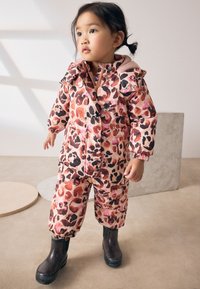 Rosa wasserdichter Schneeanzug mit Leopardenmuster und Kapuze; elastische Bündchen und Beinabschlüsse; kombiniert mit schwarzen glitzernden Regenstiefeln.