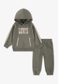 Sweatshirt khaki avec le logo "LEVI'S" et un pantalon de survêtement assorti, présentant des bandes latérales contrastées et des poches avant, adapté pour un style décontracté.