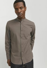Long-sleeve button-up shirt in muted brown fabric, featuring a band collar, brown buttons, and a straight cut.