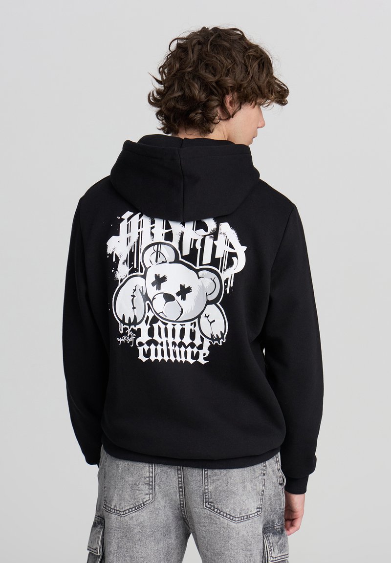 Felpa nera con cappuccio caratterizzata da una grande grafica bianca sul retro, che raffigura un orso con tratti esagerati e il testo "Hybrid Culture" in carattere stilizzato.