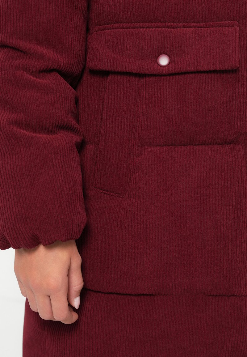 Chaqueta de pana burdeos con un gran bolsillo frontal con cierre a presión y un dobladillo de manga fruncido para un acabado texturizado.