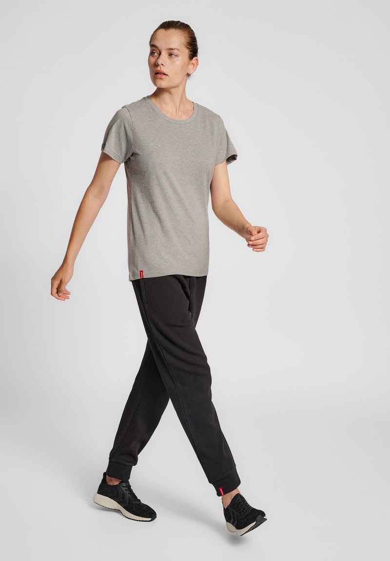 Grå kortærmet t-shirt kombineret med sorte sweatpants. Outfittet inkluderer sorte sneakers med en struktureret overdel og røde accenter.