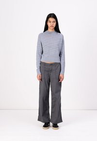 Light blue knitted sweater with a textured pattern and round neckline, paired with gray wide-leg trousers and black sneakers with a beige sole.