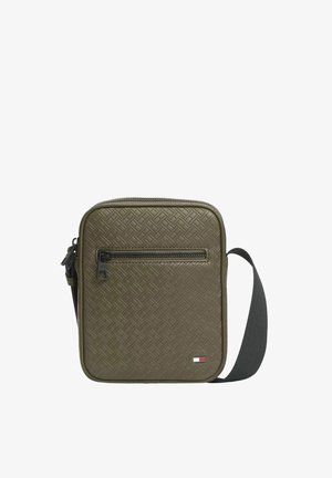 Petit sac bandoulière vert olive compact avec texture tissée, poche avant zippée, sangle noire réglable et petit logo rectangulaire dans le coin inférieur.