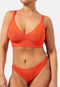 Punainen bralette ja bikinit, jotka on valmistettu sileästä kankaasta. Niissä on V-pääntie, säädettävät hihnat ja minimalistinen leikkaus.