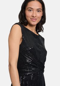 Czarna sukienka ozdobiona cekinami, z dopasowaną górą, okrągłym dekoltem i skręconym detalem w talii. Gładka faktura.
