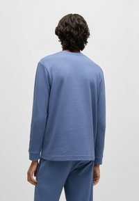 Langarmige blauwe wafelstructuurshirt met een textuurpatroon, ronde halslijn en een ontspannen pasvorm, gecombineerd met bijpassende broek.