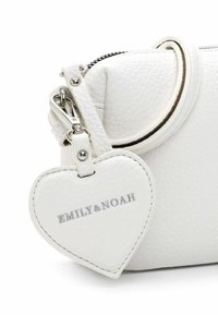 White textured leather bag with a detachable heart-shaped tag engraved with "EMILY & NOAH" attached near the zipper.