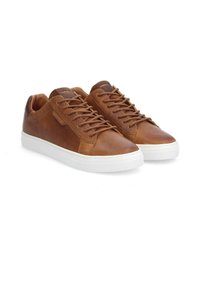 Baskets en cuir marron avec semelles en caoutchouc blanc, design à lacets, panneaux en cuir contrastants et logo discret sur la languette.