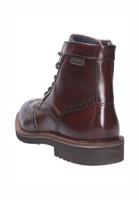 Bruine leren veterschoen tot de enkel met een ronde neus, decoratieve stiksels en een getextureerde rubberen zool. Beschikt over een zijrits en een logotag.
