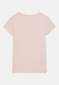 Camiseta de algodón rosa claro con mangas cortas, escote redondo y textura suave. Vista trasera sin patrones ni elementos visibles.