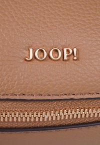 Borsa in pelle strutturata marrone chiaro con zip dorata e logo "JOOP!" in rilievo. Finitura liscia con dettagli in grana pronunciati.