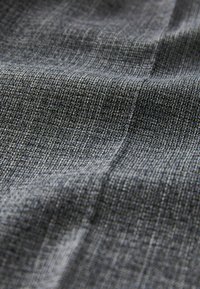 GrauTextil mit einer fein gewebten Textur, die ein dezentes Muster aus hellen und dunklen Fäden zeigt und so Tiefe und Dimension schafft.