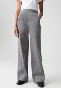 Grijze corduroy wijde-lijnbroeken met een gestructureerde oppervlakte, twee zijzakken en een hoge taille, gestyled met een eenvoudige witte t-shirt en zwarte schoenen.