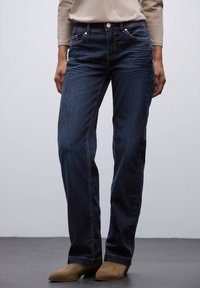 Jeans blu scuro in denim con un design a gamba dritta, caratterizzati da un classico stile a cinque tasche e sottili dettagli di cucitura.