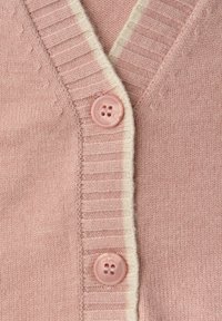 Růžový cardigan s výstřihem do V, ribázovým texture a krémovobílým lemem. Dvě kulaté růžové knoflíky jsou viditelné vpředu.