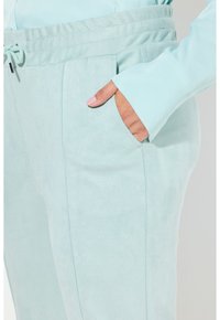 Jasnoniebieskie, miękkie i teksturowane spodnie dresowe z elastycznym paskiem w talii i bocznymi kieszeniami; charakteryzują się starannym wykończeniem szwów.