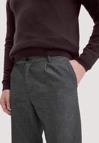 Grau strukturierte Hose mit vorderen Taschen und Knopfverschluss, kombiniert mit einem weinroten gestrickten Pullover mit gerippten Bündchen.