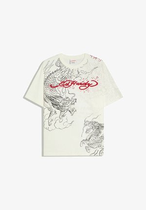 Bijela majica s crnim skicama zmaja i crvenim natpisom "Ed Hardy" preko prsa, kratkih rukava i okruglog izreza.