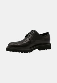 Chaussure derby en cuir noir avec une finition lisse, des détails perforés et une semelle en caoutchouc épaisse présentant un motif de bande de roulement robuste.
