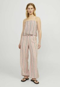 Twee-delige outfit bestaande uit een cropped gestreepte top en wijde broek in tinten roze, crème en grijs. Gemaakt van lichte stof.