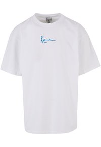 Bijela pamučna majica, slobodnog kroja, s svijetloplavim izvezenim logotipom na prsima. Kratki rukavi i okrugli izrez.
