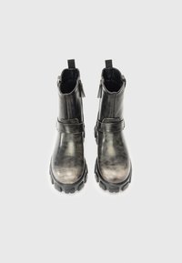 Para czarnych skórzanych botków za kostkę z grubą podeszwą i bocznymi zamkami, zaprezentowanych z przodu na białym tle.