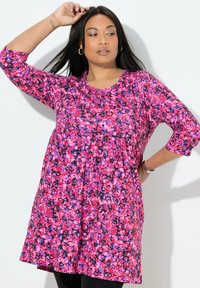Kwiatowa sukienka tunikowa o żywym wzorze w kolorach różowym, fioletowym i czarnym, z okrągłym dekoltem i rękawami o długości do łokcia. Luźny materiał z marszczeniem.