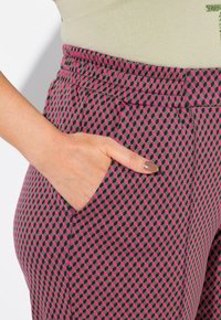 Hoge taillebroek in een geometrisch patroon van roze, zwart en grijs, voorzien van een zijzak en een gestructureerde stof voor comfort.